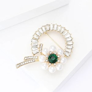 Elegant floral brooch with gold metal, emerald gemstone, pearls, and sparkling crystals