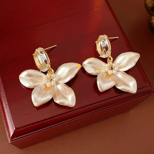 Detail of floral earrings with pearl petals and clear crystals on a vintage wooden box
