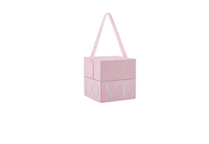 Gros plan sur la boîte cadeau rose avec ruban LOVE IS ETERNAL et surface texturée