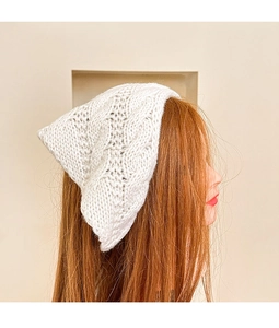 Detailed close-up of white knitted crochet floral headband with hollow pattern texture