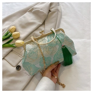 Detail of mint green shell bag with floral embroidery, tassel, and gold chain strap