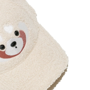 Gros plan sur une casquette en polaire blanche avec broderie ours et yeux en relief