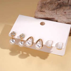 Elegantes 6-teiliges Gold-Ohrring-Set mit Perlen und Diamanten auf Natursteinhintergrund
