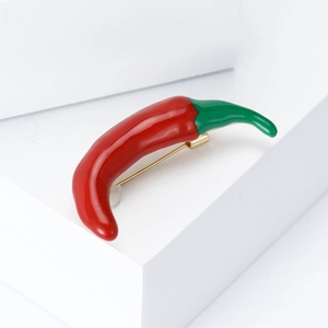 Creative red enamel chili brooch with green stem on white minimalist geometric block