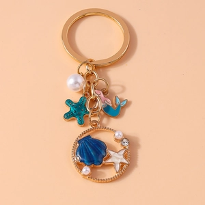 Detail of ocean-themed keychain with starfish, mermaid charms, and faux pearls on gold chain