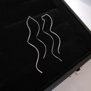 Detail view of silver wave-shaped drop earrings on a black velvet display background