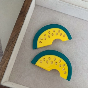 Macro detail of watermelon acetate earrings with green rind and yellow pulp texture