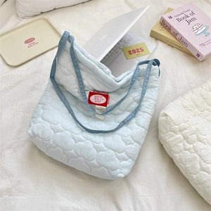 Detailed view of light blue quilted bag with heart stitching and red inner logo label