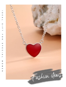 Detailed view of red heart pendant necklace on minimalist chain with decorative white stones