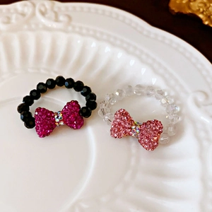 Close-up of beaded bow rings with colorful crystals on a white ceramic display tray