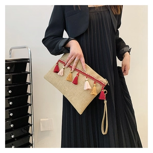 Close-up of a straw envelope bag featuring ethnic tassels and woven strap decoration