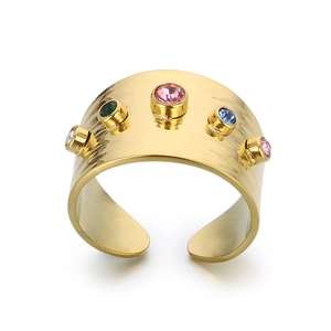 Golden wide band geometric ring with colorful zircon stones on a white background