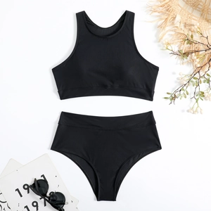 Flat lay of a sporty black high-waisted two-piece swimsuit with beach lifestyle props