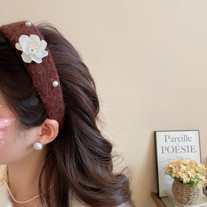 Detail of elegant brown velvet headband with white flower and pearls on model
