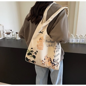 Detail of canvas tote bag with cute animal patterns worn by a model in casual setting