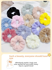 Flat lay of colorful plush faux fur hair scrunchies on white textured fabric background
