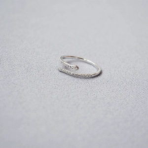Macro shot of silver snake-shaped ring featuring sparkling pavé crystals on a soft grey cloth