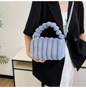 Blue fuzzy handbag detail with beaded handle and leather strap on a model wearing black