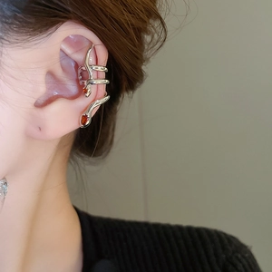 Detailed close-up of a silver snake ear cuff with red zircon stones on a female ear