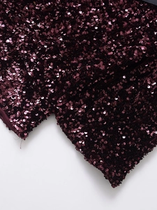 Macro detail of wine red sequin dress showing dense metallic texture and reflective shine