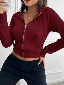 Detail of red ribbed knit hoodie showing the zipper closure and front pocket texture