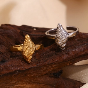 Macro view of gold and silver conch rings with 3D pleated texture on dark wood background