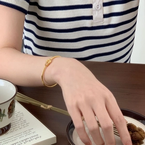 Close-up of a 18K gold-plated knotted bangle with micro-pave white zircon details