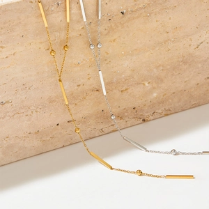 Detail of minimalist gold and silver Y-shaped necklaces with bar and bead pendants