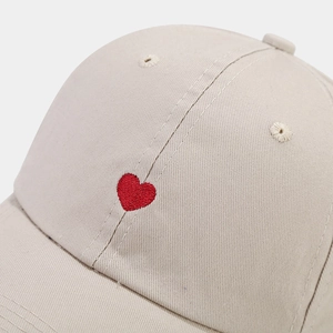 Minimalist beige cotton baseball cap with a small red embroidered heart on the front