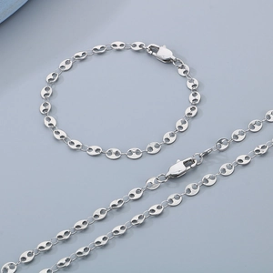 Silver pig nose coffee bean link necklace and bracelet set on a light gray background