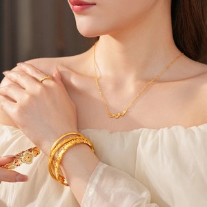Detailed view of vintage gold brushed jewelry set with wavy pendant and textured bracelets