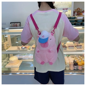 Pink plush capybara backpack with a blue cap and pink nylon straps on a female model