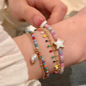 Detail of colorful beaded bracelets with gold stars and pearls on a woman wrist