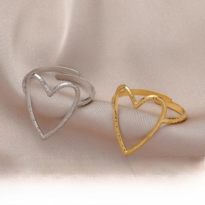Macro shot of gold and silver heart-shaped open rings with textured finish on silk