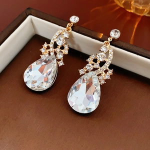 Détail de boucles d'oreilles de luxe en cristal goutte avec pampilles dorées en boîte