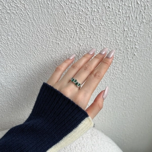 Detail of S925 sterling silver ring with large green gemstone and clear side stones
