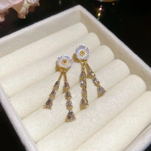 Detail of floral tassel earrings with gold finish and crystal teardrops in jewelry box