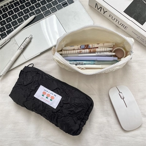 Close-up of cloud-textured pleated pencil cases in black and off-white with zipper