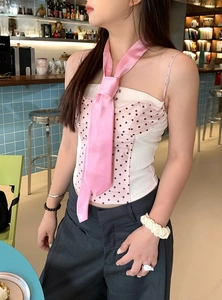 Close-up of a sweet pink satin necktie styled with a polka-dot corset top in a cafe setting.