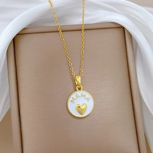 Gold necklace with white MAMA heart pendant on white silk fabric background