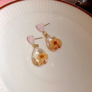 Dettaglio orecchini a cuore rosa con ciondoli a goccia in resina e fiori essiccati
