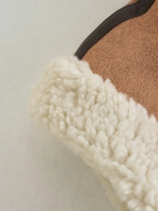 Detailed macro view of brown faux suede vest with soft sherpa lining and leather piping