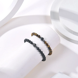 Detaillierte Nahaufnahme von Lavastein- und Tigerauge-Armbändern auf minimalistischer Deko