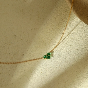Detailed view of gold chain necklace with three irregular square green crystals