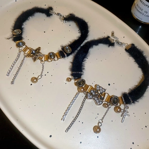 Detail of plush black chokers with star tassels and pearl cross charms on a tray