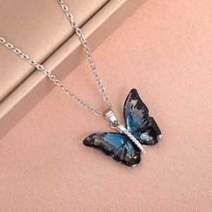 Detailed close-up of acrylic butterfly pendant with blue dye and gold foil accents