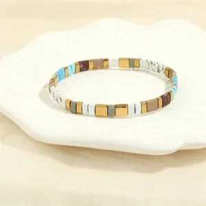 Close-up of bohemian TILA bead stretch bracelet with colorful square enamel tiles