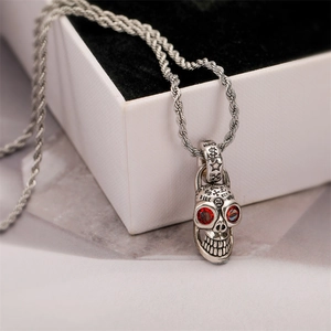 Makroaufnahme von Silber Totenkopf Anhänger mit roten Edelsteinaugen und Gravuren