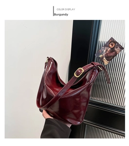Close-up of wine red hobo bag showing glossy patent leather and gold metal hardware