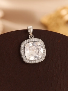 Macro shot of silver square pendant with large clear gemstone on brown leather surface